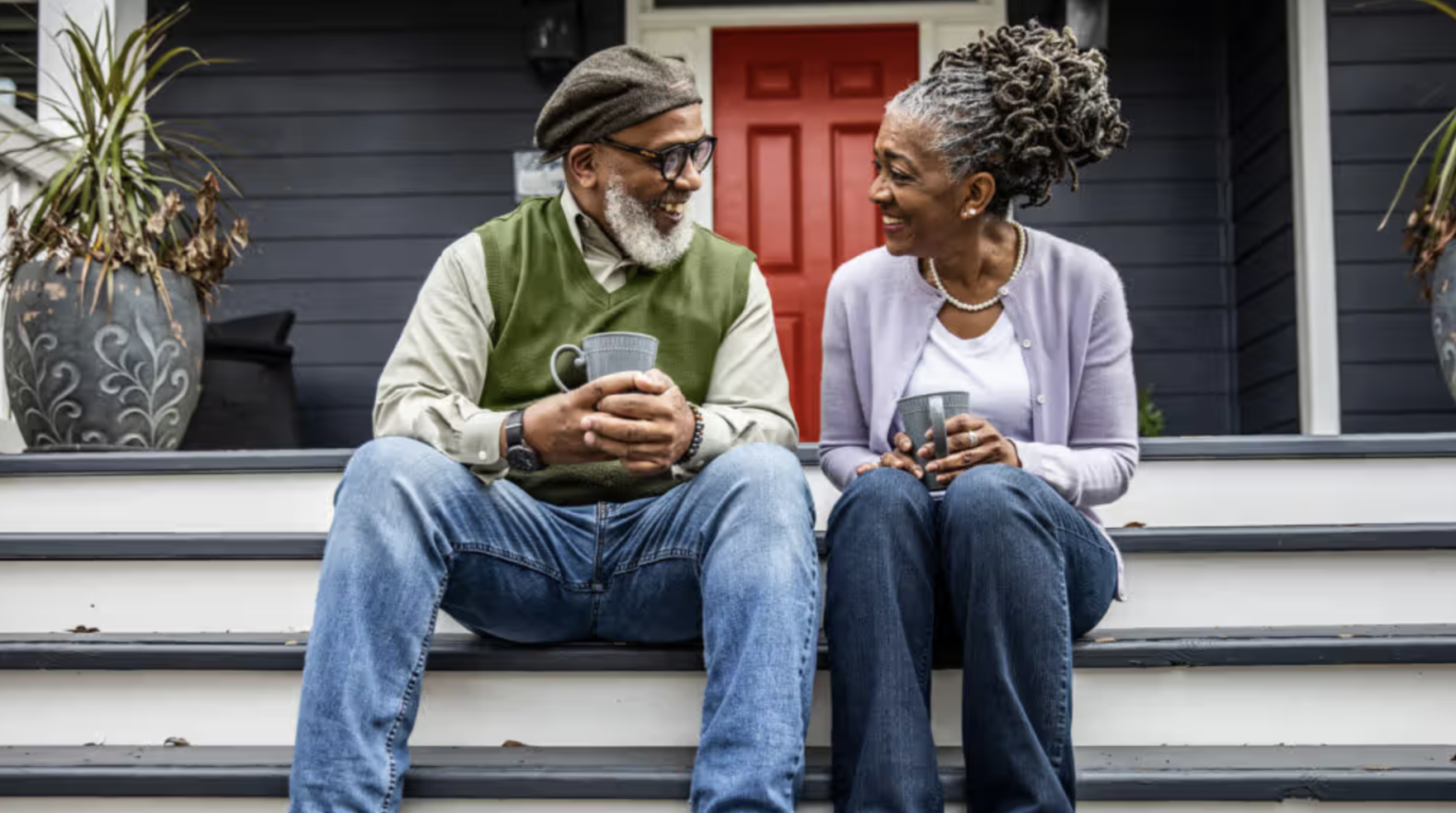 Smiling couple sitting on their front porch with coffee